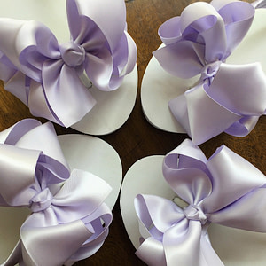 Large lavender coloured bows on high wedge heel flip flops