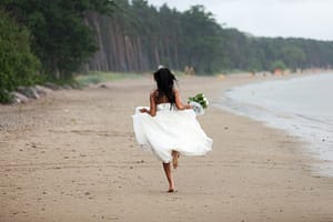 A Bride running down the Beach without any shoes on