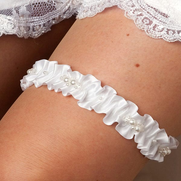 Bride wearing white bridal garter with pearl embellishments